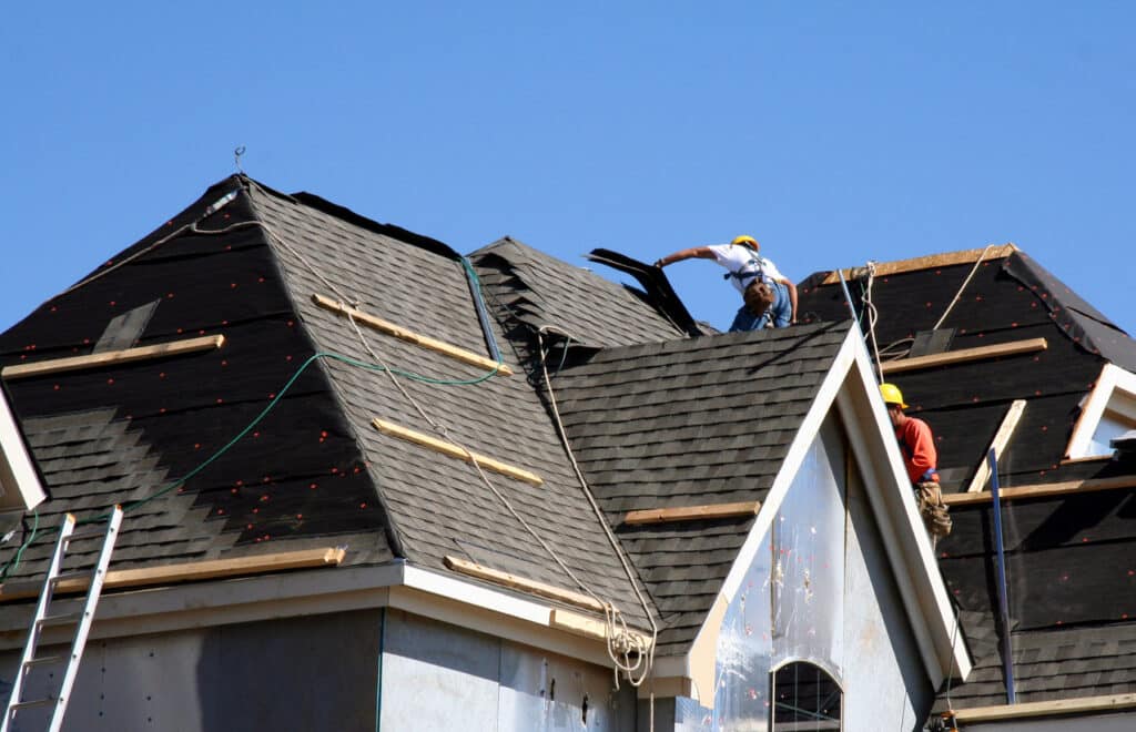 workers putting shingles on roof