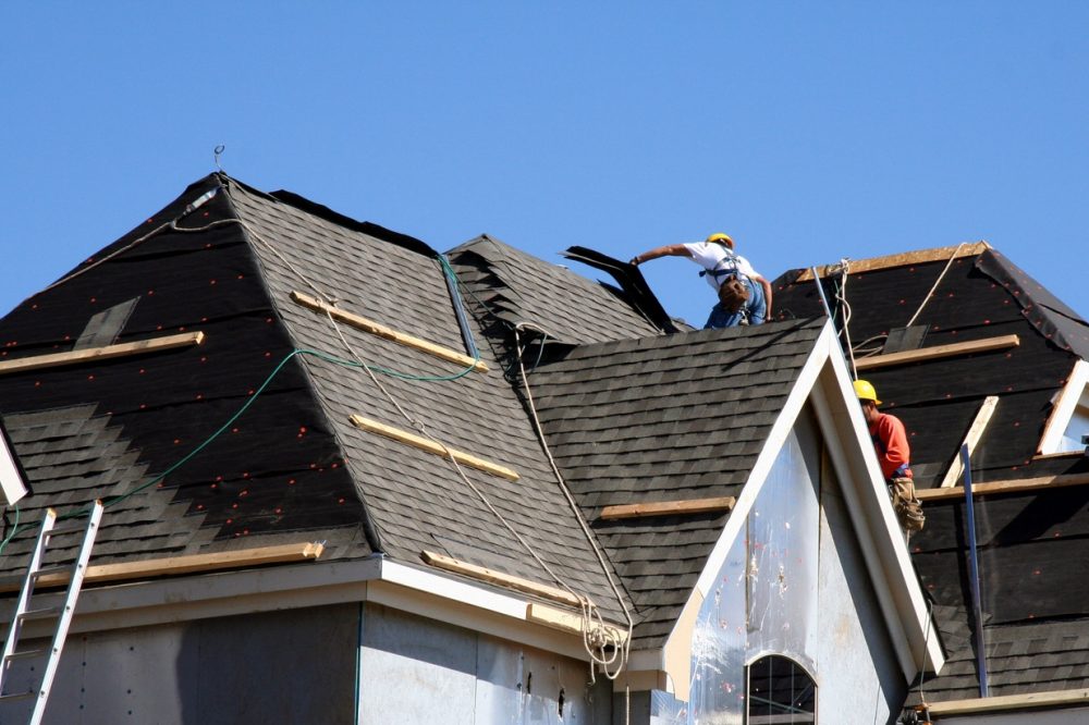 Construction-workers-putting-shingles-on-the-roof-of-a-house.-